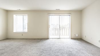 A room with a carpeted floor, a window, and a sliding door
